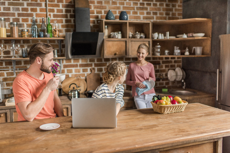 little girl using laptop with parents in kitchenの写真素材