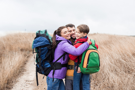 Happy family with backpacks huggingの写真素材