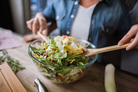 Close-up partial view of mature couple cooking vegetable salad in bowlの写真素材