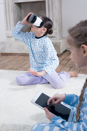 girls with Virtual reality headset and digital tablet sitting on carpetの写真素材