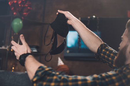 young man holding black bra after partyの写真素材