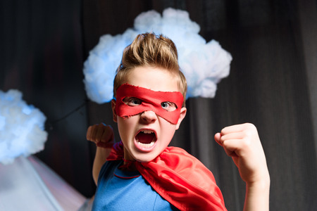 boy in red superhero costume with fighting gesture screamingの写真素材