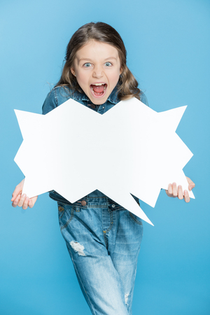 little girl in denim overalls holding speech bubble and screamingの写真素材
