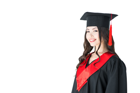young brunette woman in mortarboard smiling at looking at cameraの写真素材