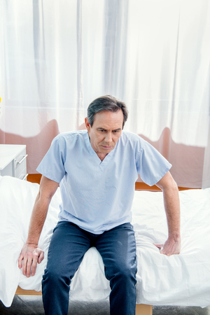 middle aged patient sitting on bed in chamberの写真素材