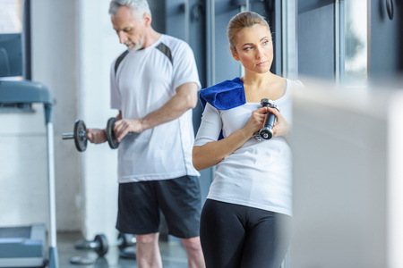 sportswoman and senior sportsman training with dumbbellsの写真素材