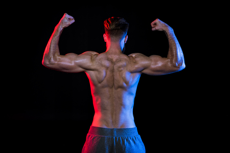 shirtless bodybuilder gesturing isolated on black with dramatic lighting