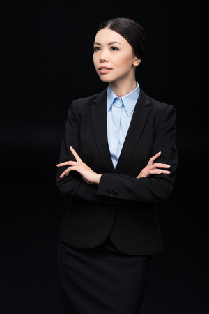 brunette businesswoman in black suit with crossed armsの写真素材