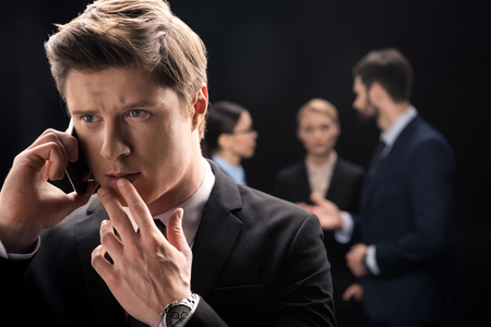 pensive businessman using smartphone while business people connecting behindの写真素材