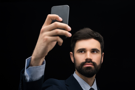 serious businessman taking selfie on smartphoneの写真素材