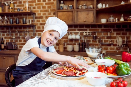 little smiling boy making pizzaの写真素材