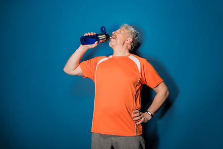 Athletic mature man drinking water from sports bottleの写真素材