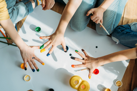 kids painting on paper with hands while sitting on floorの写真素材