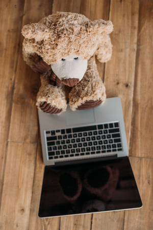 teddy bear toy and laptop on floorの写真素材