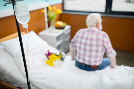 Senior man with flowers in hospitalの写真素材