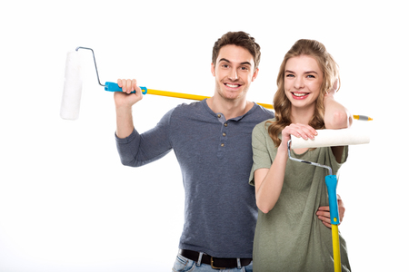 young professional couple holding paint rollers isolated on whiteの写真素材