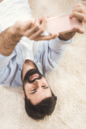 man taking selfie while lying on carpetの写真素材