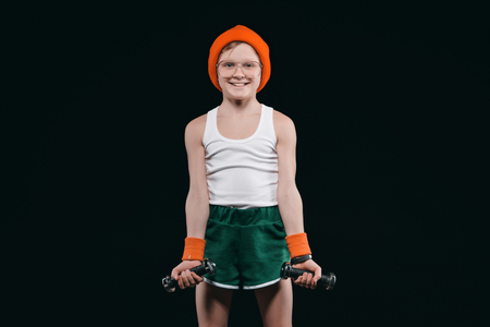 boy training with dumbbells isolated on blackの写真素材