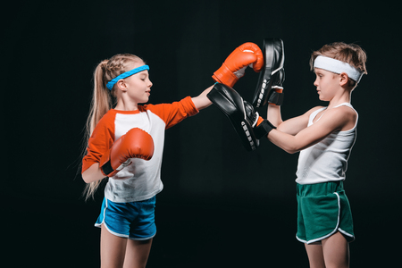side view of kids pretending boxing isolated on blackの写真素材
