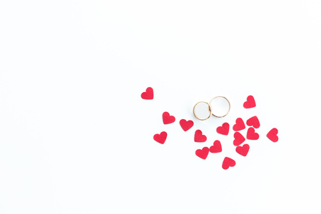 Top view of golden wedding rings and pink hearts symbols isolated on whiteの写真素材