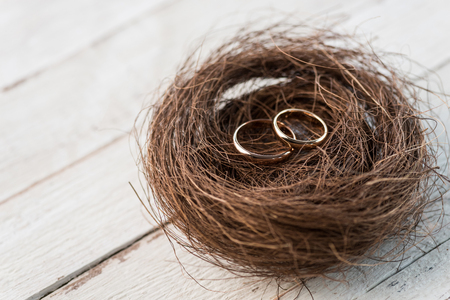 golden wedding rings in decorative nest on wooden tabletopの写真素材