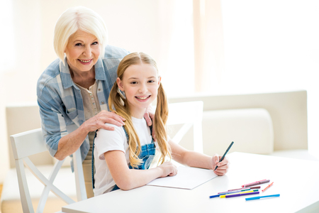 girl and senior woman drawing together and smiling at cameraの写真素材