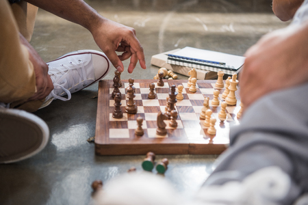 young men sitting on floor and playing chess on chess boardの写真素材