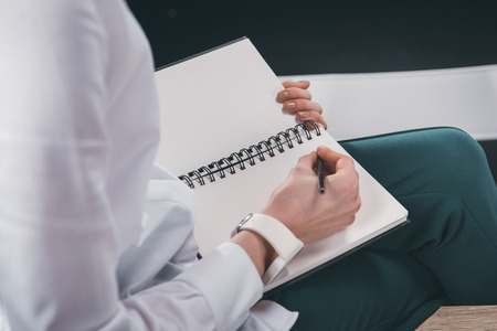 Cropped image of woman writing notes in notepadの写真素材