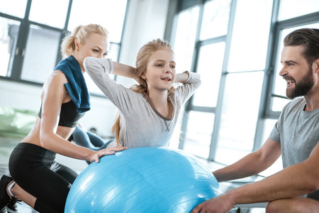 girl exercising on swiss ball with parents