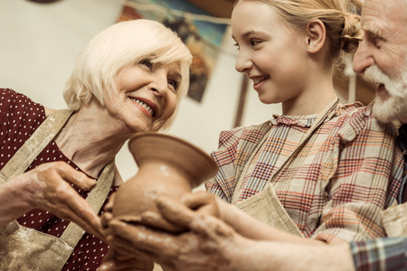 Grandmother and grandfather with granddaughter holding clay vase