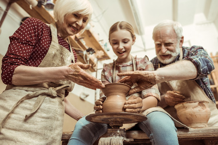 Grandmother and grandfather with granddaughter making potteryの写真素材