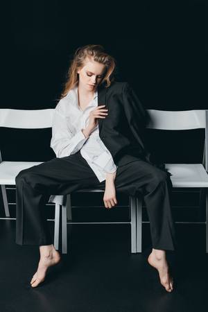 Woman in male shirt sitting on chairsの写真素材