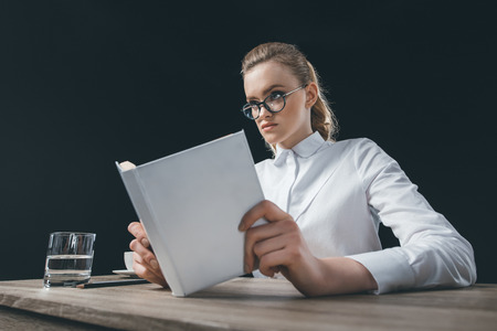 woman sitting at table with book in handsの写真素材