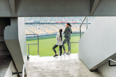 two young sportswomen standing at handrail on stadiumの写真素材