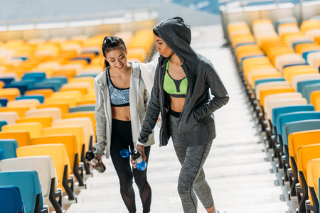 young sportswomen with sport bottles on stadium stairsの写真素材