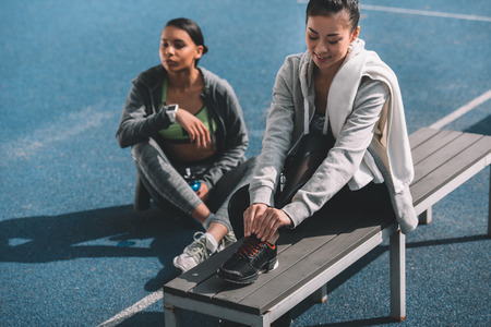 young women in sportswear resting together on stadiumの写真素材