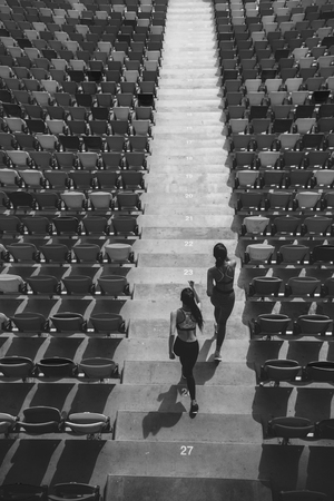 two sportswomen running on stadium stairsの写真素材