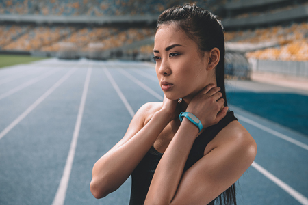 asian sportswoman standing on running track stadium and looking awayの写真素材