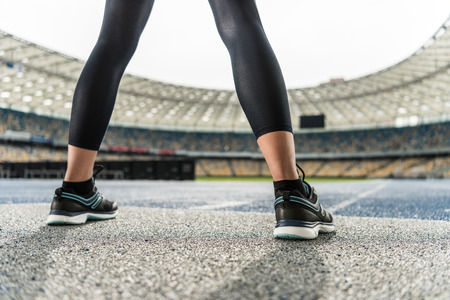 young sportswoman in sneakers standing on running track stadiumの写真素材