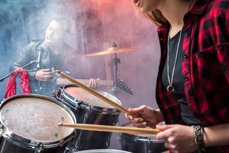 side view of woman playing drums and man singing into microphoneの写真素材
