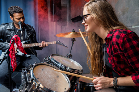 side view of woman playing drums with man playing guitarの写真素材