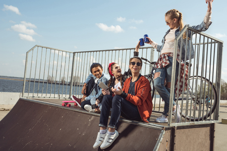 teenagers having fun with smartphone in skateboard parkの写真素材