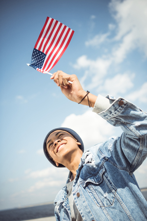 smiling african american teenager waving american flagの写真素材