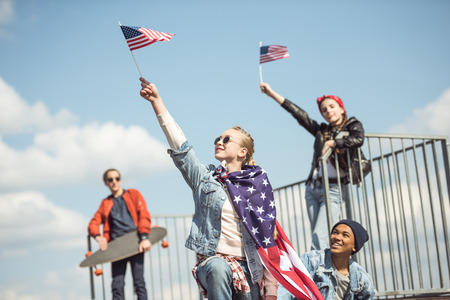 Teenagers group having fun together and waving american flagsの写真素材