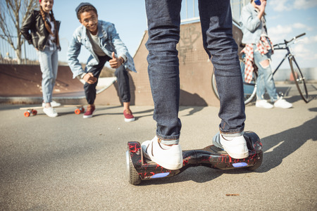 stylish hipster boy riding gyroboard with friends near by