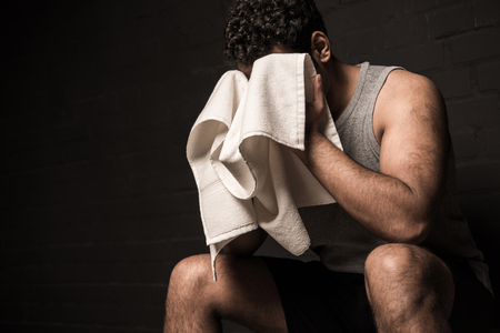 handsome man wiping face by towel at gym locker roomの写真素材