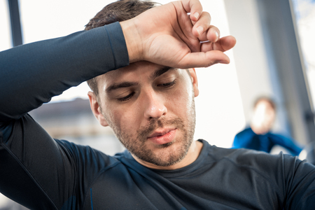Tired young man wiping face by handの写真素材