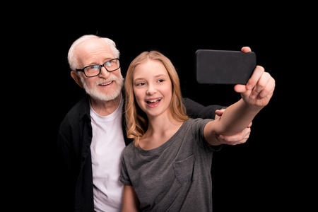 Grandfather and granddaughter taking selfieの写真素材