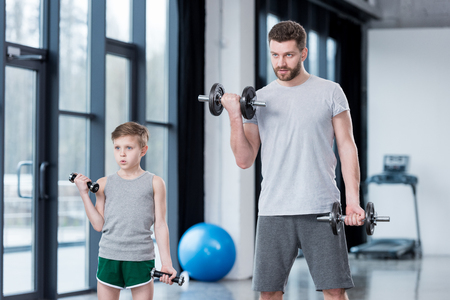 Boy training with dumbbells together with coachの写真素材