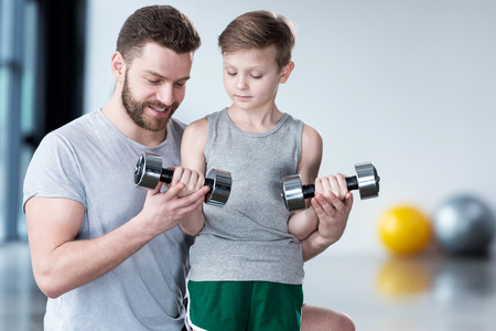 Boy training with dumbbells together with coachの写真素材